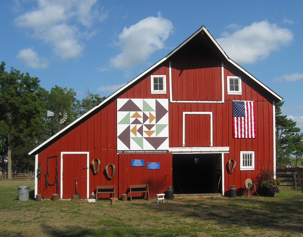 Red barn with a barn quilt and American flag