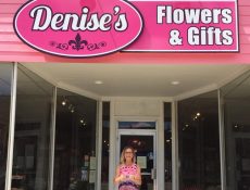 Woman smiling underneath Denise's Flowers & Gifts sign