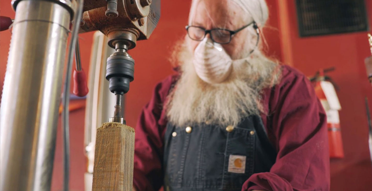 Man wearing a dust mask works with lathe