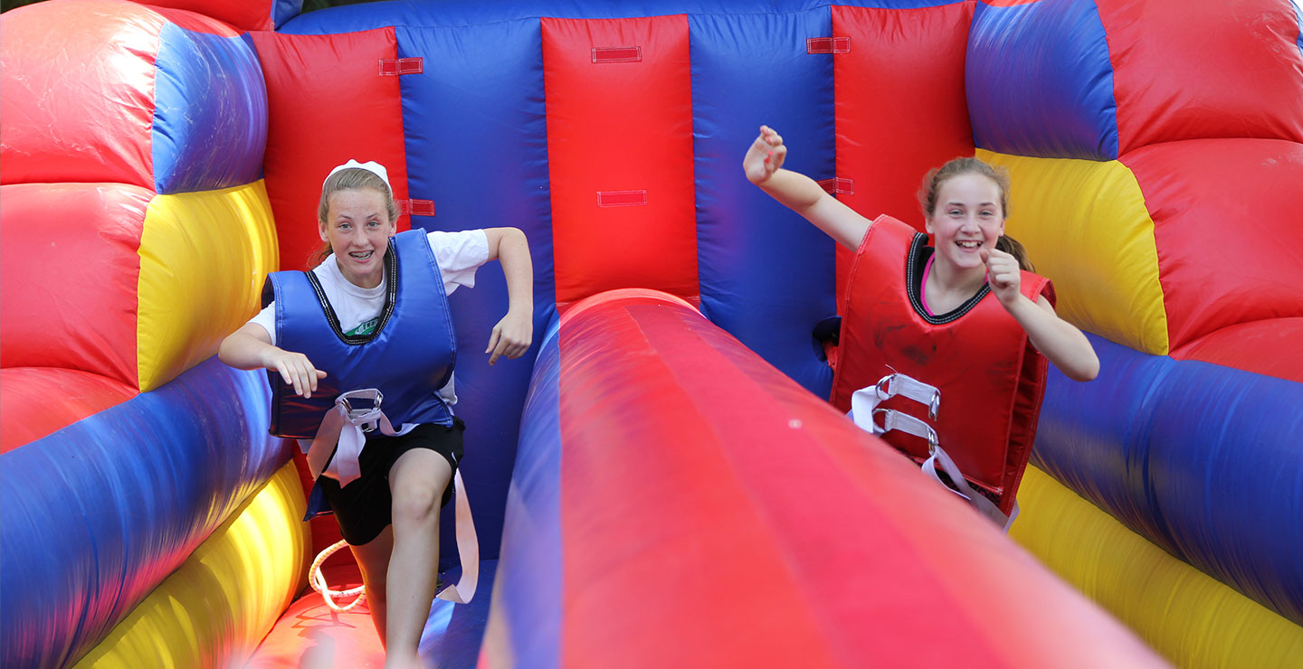 Two young girls running on an inflatable obstacle course