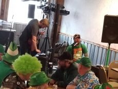 Bar customers dressed in St. Patrick's Day clothing sit around table