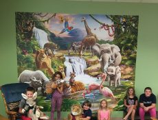 Children posing in front of a jungle mural