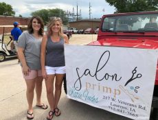 Salon Primp owners pose next to branded banner