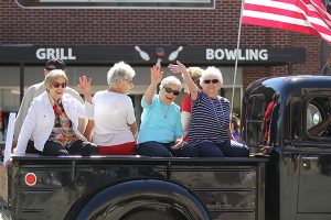 Women waving while riding in a truck bed