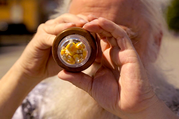 Man looking through kaleidoscope with yellow corn kernels