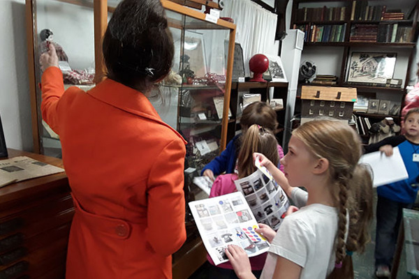 Tour guide explaining items in a display case to group of children