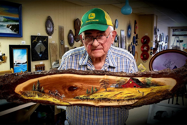 Man holds wooden slab with oil painting
